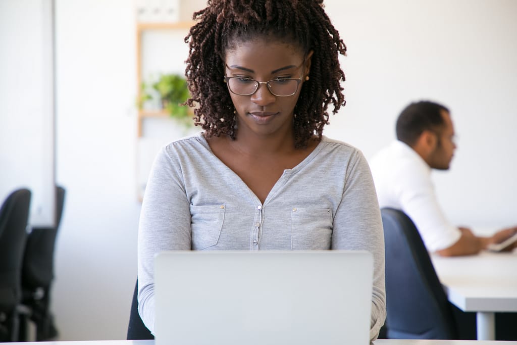 Focused pensive African American worker using laptop